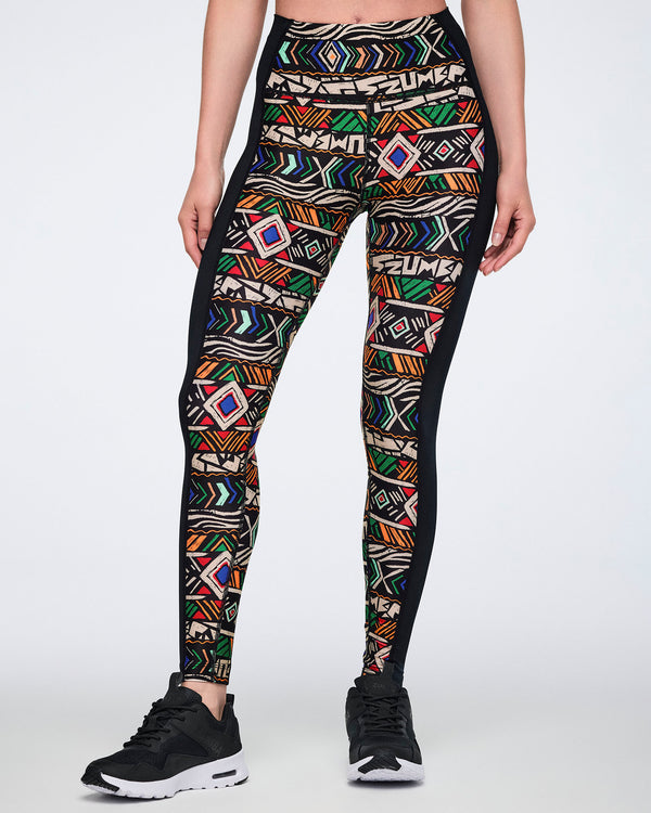 Front view of high-waisted full-length leggings with a multicolor geometric print on the front and solid black side panels. Female model wears the fitted leggings with black athletic sneakers.