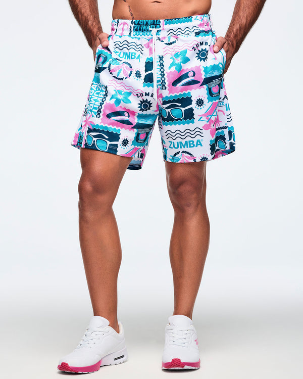 Front view of white elastic-waist drawstring shorts with a teal-and-pink Zumba graphic print and white drawcord; shown on a male model with white sneakers.