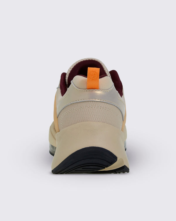Heel view of a beige platform shoe, showing an orange pull tab with a Zumbito logo, burgundy lining, a metallic gold heel panel, and a rounded black outsole.