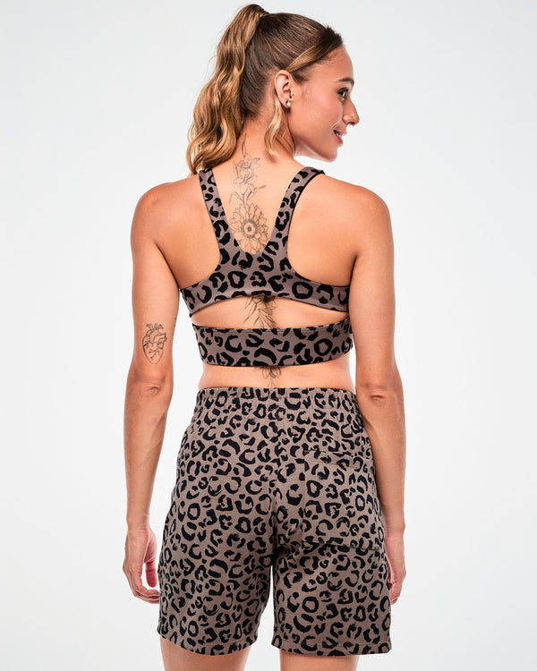 Back view of a female model in the brown leopard print racerback bra with a keyhole cutout, paired with matching leopard print shorts.