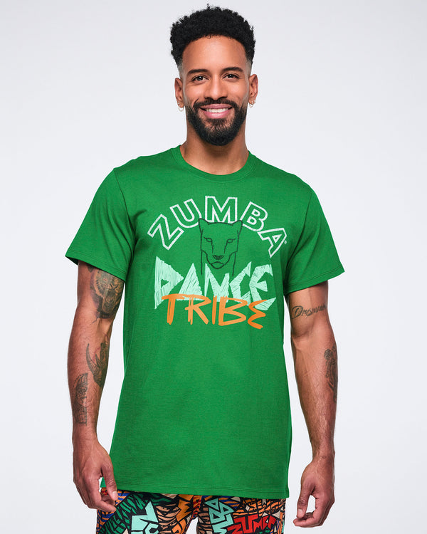 Green short-sleeve Zumba graphic T-shirt with a crew neckline and relaxed fit, featuring a front “Zumba Dance Tribe” design with a lion graphic in white, mint, and orange. Male model wears the T-shirt with multicolor print pants.