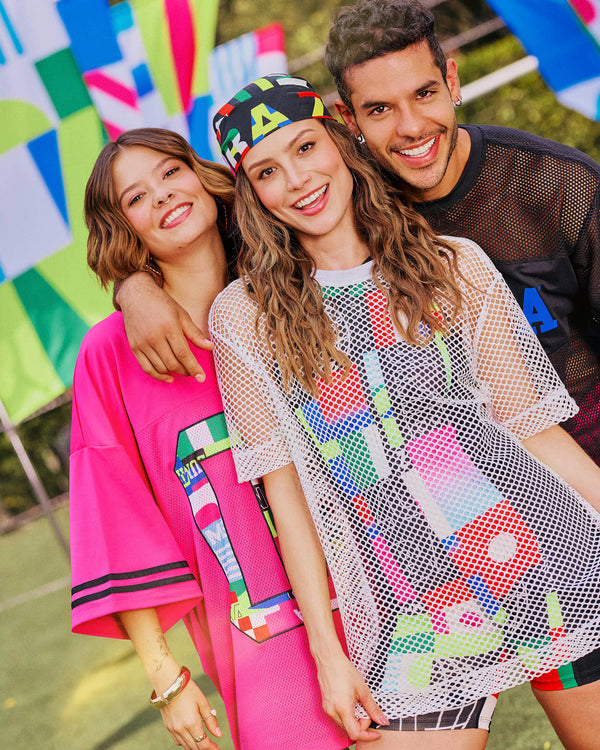 Three models (2 female and 1 male) posing together with colorful Zumba clothing and a vibrant outdoor background.