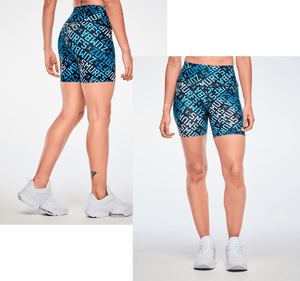 Two overlapping photos of a female model's legs in high-waisted biker shorts with diagonal blue, light blue, and white 'ZUMBA' X 'THE SMURFS' lettering on black, shown from the back on the left and from the front on the right, with white shoes against a light grey background.