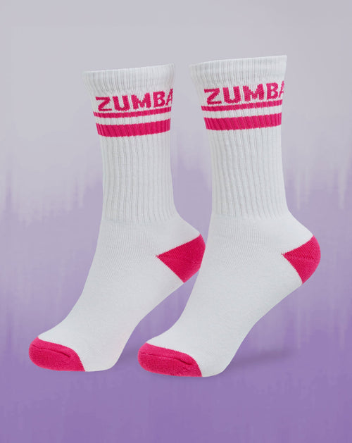 Zumba white ribbed crew socks with hot pink ZUMBA stripe and pink toe/heel accents, shown on a purple gradient background.