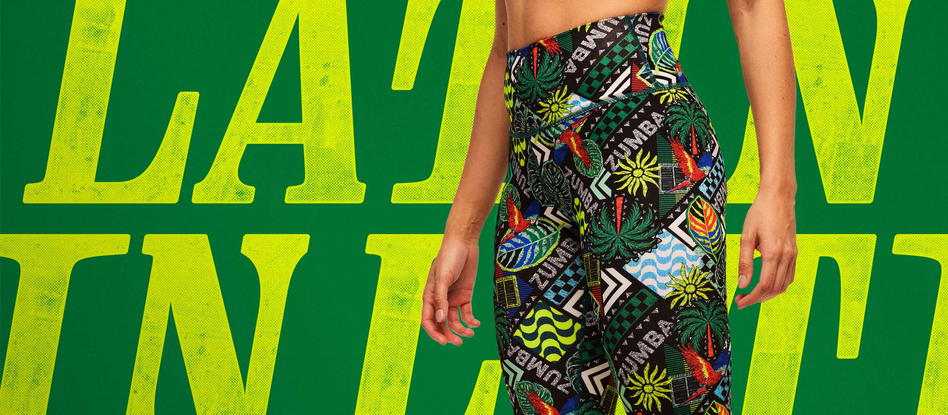 Cropped waist-to-ankle shot of a female model in bold Zumba leggings in front of oversized yellow lettering saying LATIN, on a green background.
