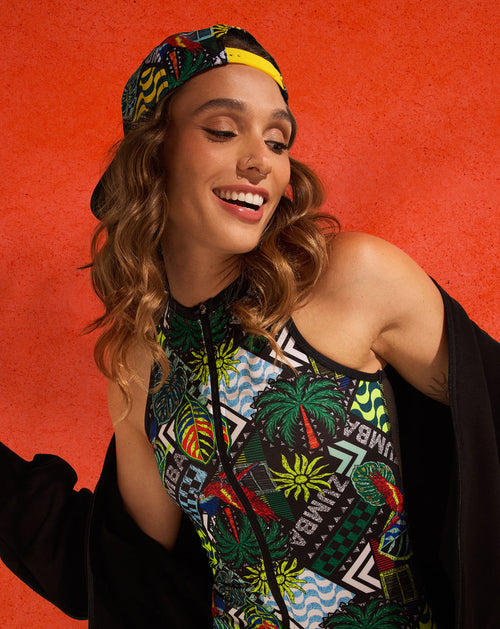 Banner of a smiling woman in colorful bodysuit against a textured orange background. The female model is also wearing a matching multi-color cap worn backward and a black jacket draped off her shoulders.