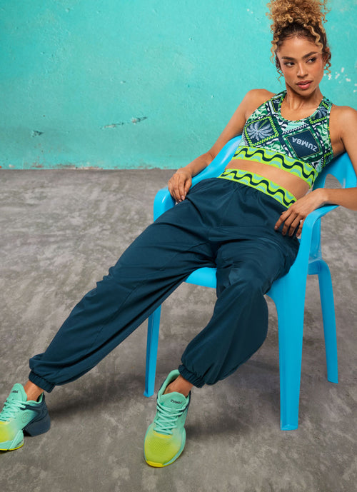 Female model reclining on a bright blue chair in front of a teal wall.