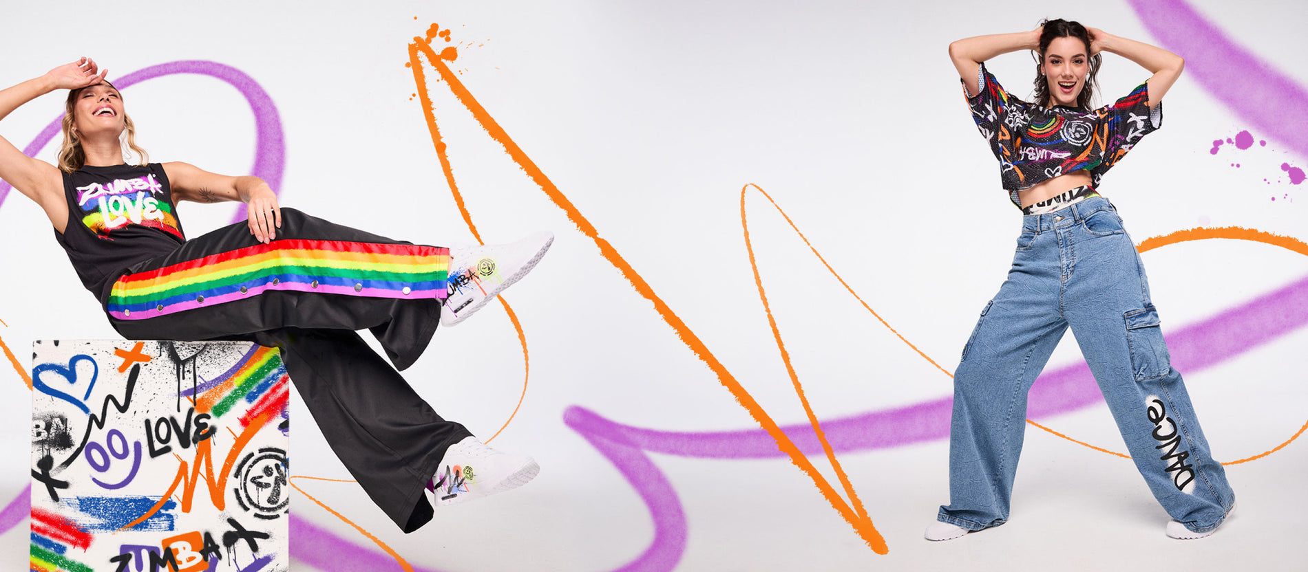 Two models in rainbow‑accented Zumba outfits posing against a white backdrop with bold orange and purple paint strokes.