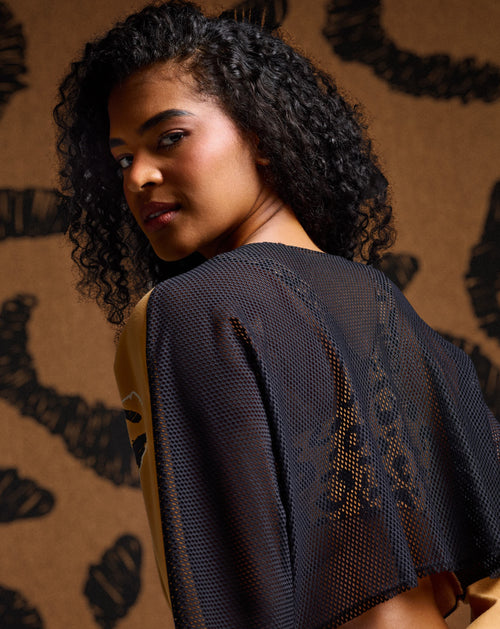 Female model is wearing a mesh backed Zumba top against a matching cheetah print background.