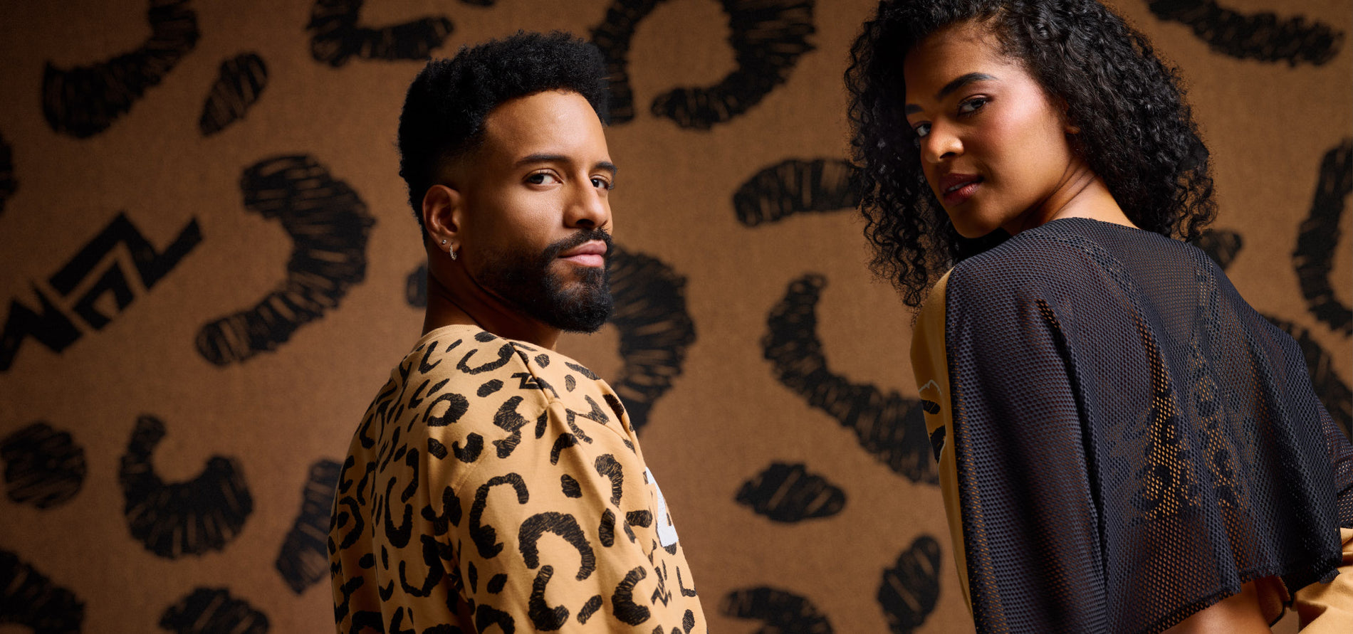 Male model is wearing a cheetah print sweatshirt and the female model is wearing a mesh backed Zumba top against a matching cheetah print background.