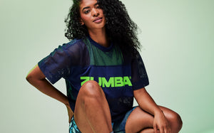 Banner of a female model in a navy mesh top layered over a green tank with matching leggings, smiling against a soft mint green background.