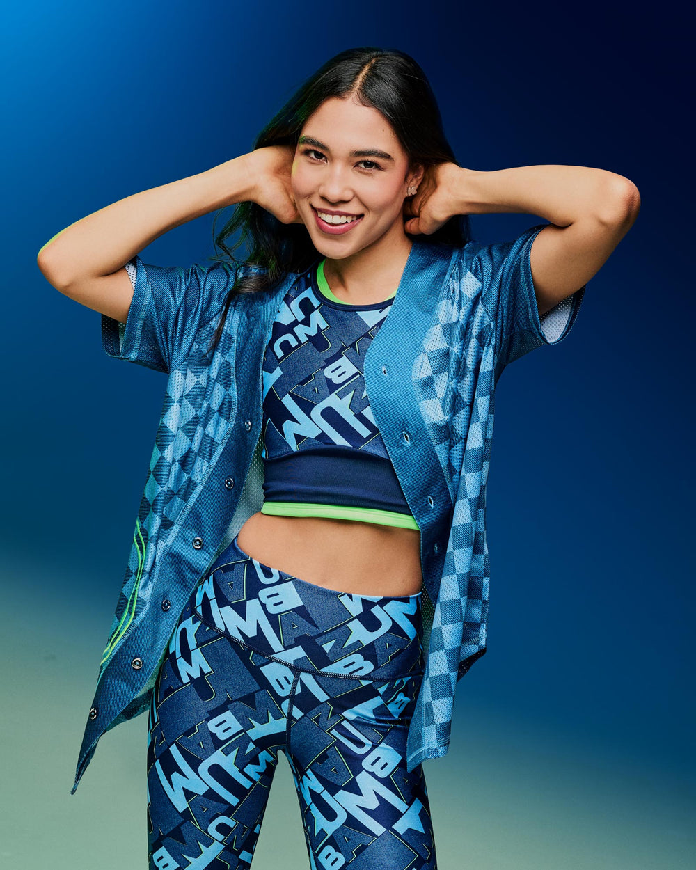Banner image of a female model in blue graphic crop top and matching leggings with a checkered open button up top, against a deep blue gradient background.