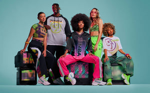 Group of five male and female models gathered around vintage TVs against an aqua background, wearing various multi-colored 