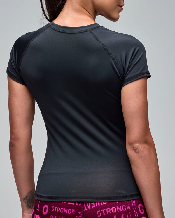 Back view of a black fitted short-sleeve performance top with a smooth athletic silhouette. Female model wears the crewneck tee with burgundy and pink printed leggings against a light gray background.