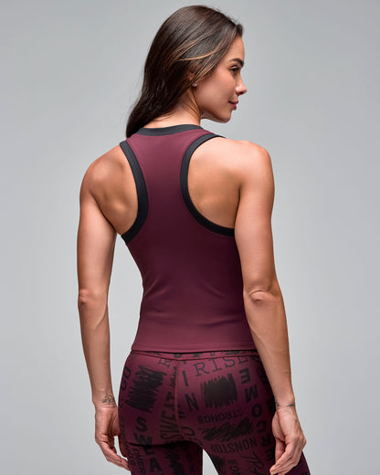 Back view of a burgundy fitted racerback tank top with black trim. Female model wears the sleeveless athletic top with burgundy motivational word-print leggings against a light gray background.