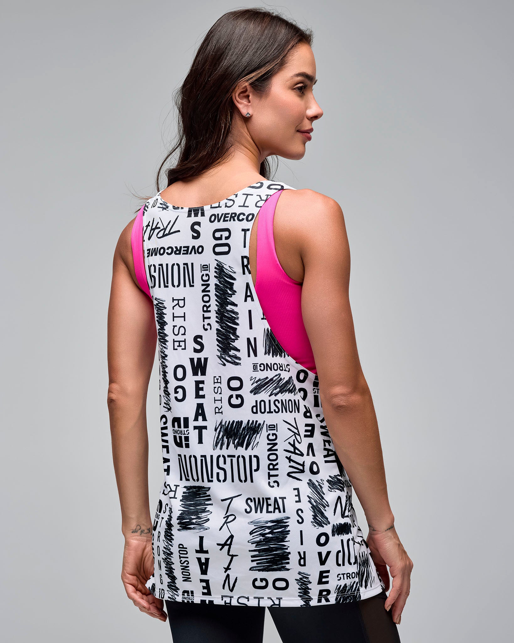 White graphic-print athletic tank with a scoop neckline and racerback-style cut, shown from the back on a female model layered over a pink sports bra and paired with black leggings.