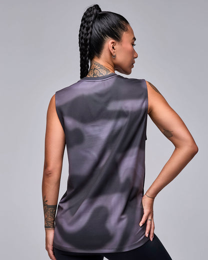 Shown from the back, a female model in the black and grey swirl print tank, with a long, loose fit and plain back.
