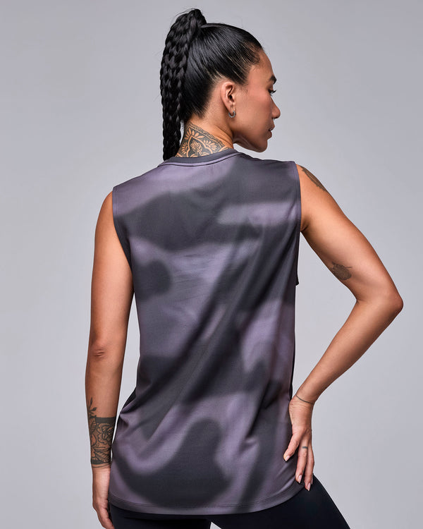 Shown from the back, a female model in the black and grey swirl print tank, with a long, loose fit and plain back.