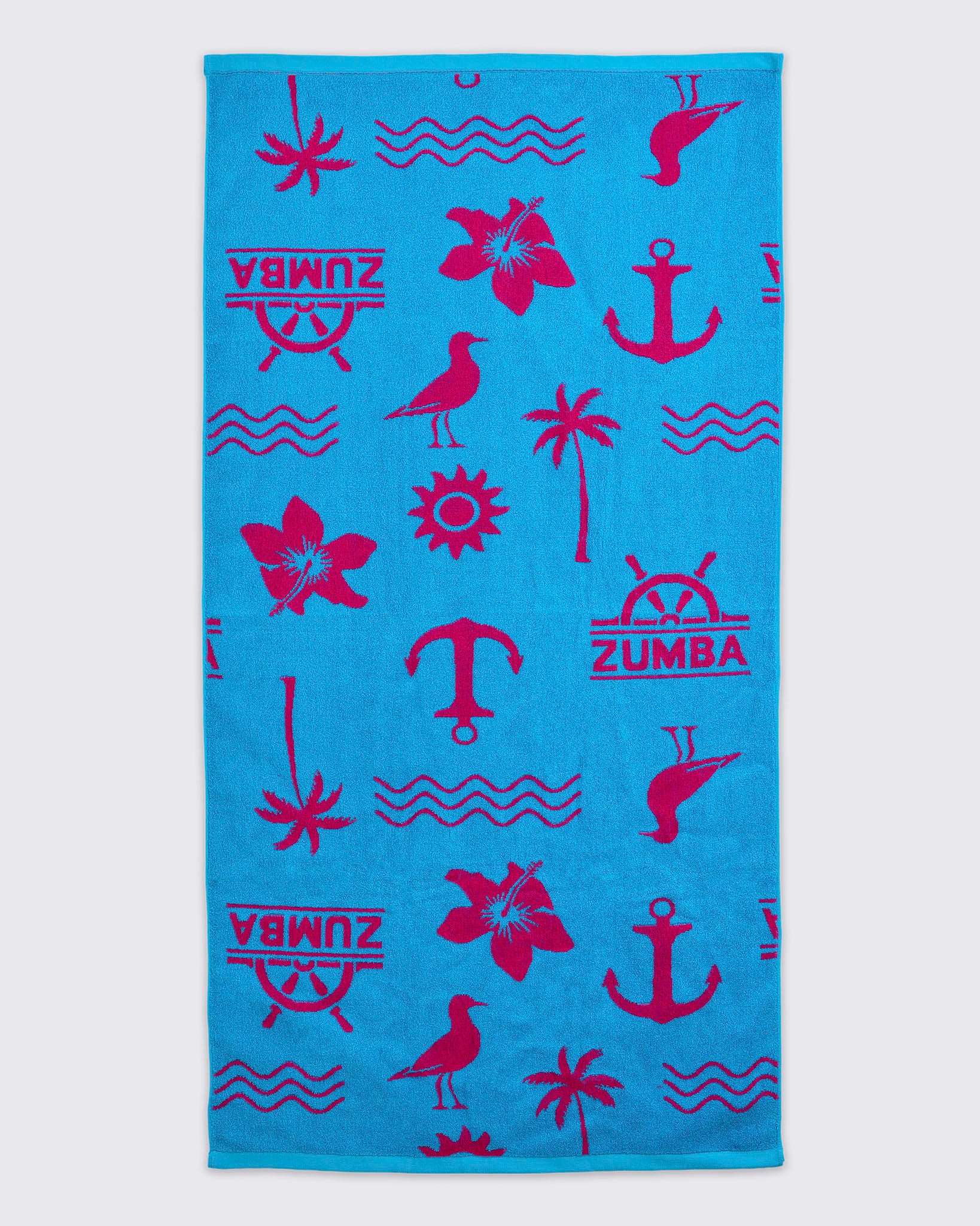 Turquoise beach towel with hot-pink Zumba logo and allover nautical icons, including anchors, palm trees, waves, flowers, and birds, laid flat on a white background.