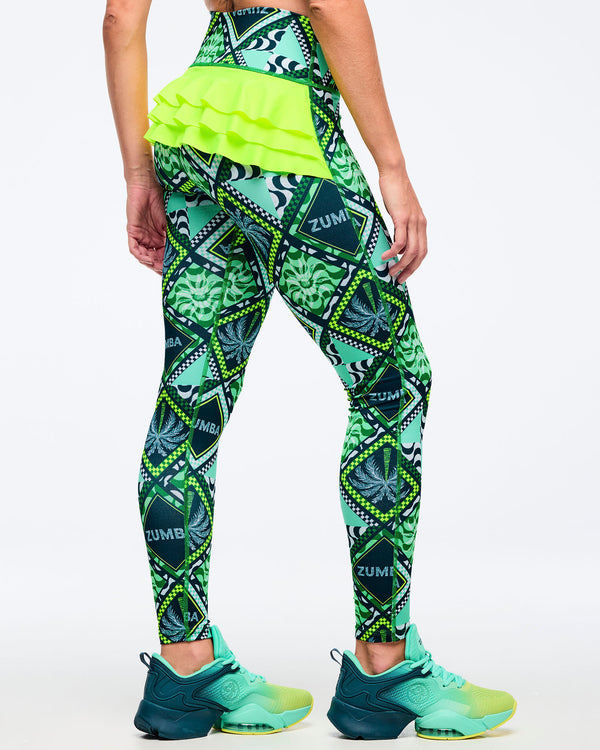 Green geometric-print high-waisted leggings with neon lime layered ruffle detail across the back waistband, shown from the back on a female model wearing teal-to-lime athletic sneakers on a white studio background.