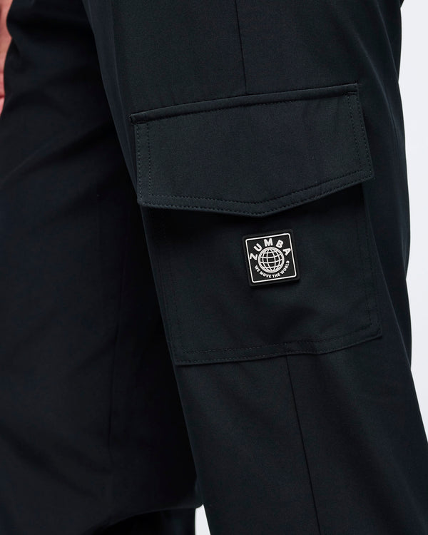Close-up of the black cargo jogger pants showing the flap cargo pocket and stitched Zumba logo patch on the thigh.