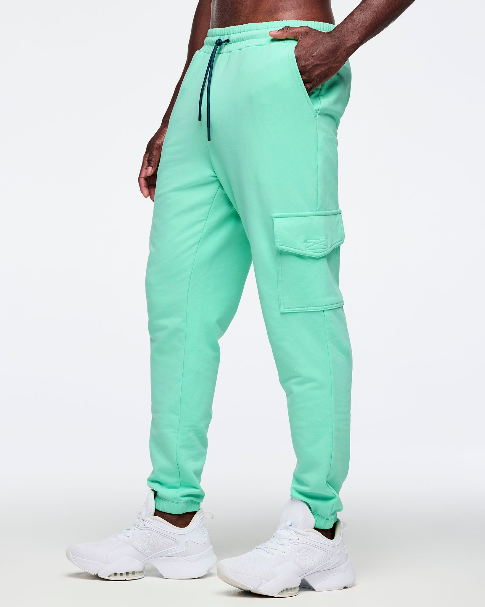 Mint green cargo jogger pants shown in side view on a male model; flap cargo pocket detail and elastic cuffs, paired with white sneakers.