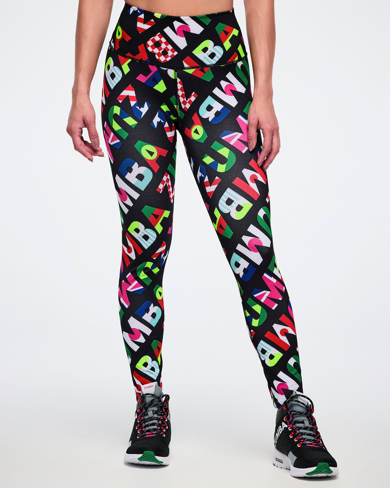 Female model from the front, wearing leggings with colorful flag-like pattern, on a white background
