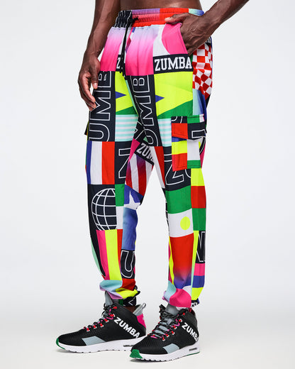 Male model wearing colorful Zumba pants with a geometric pattern on a white background.
