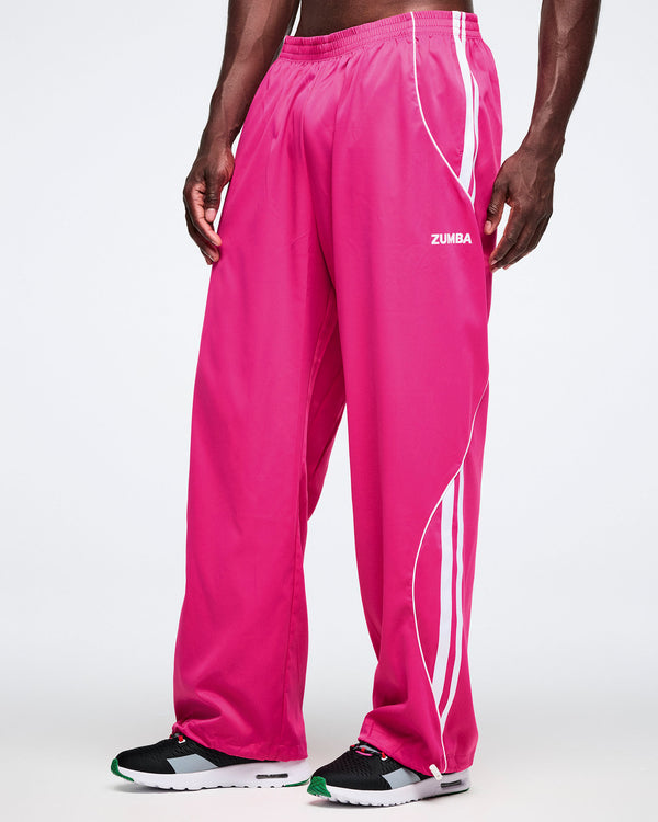 Male model wearing pink Zumba pants with white stripes on a white background.