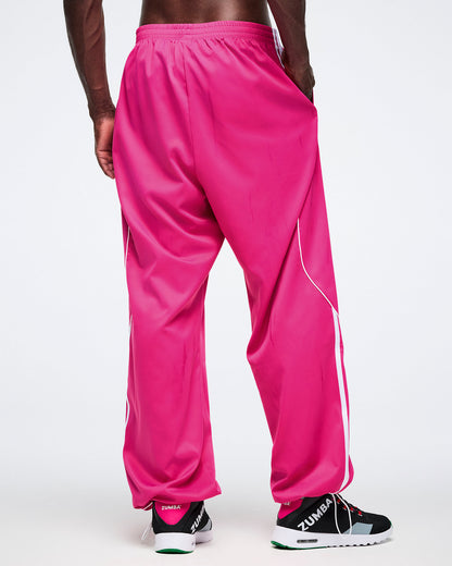 Back view of male model wearing bright pink Zumba pants with a white background.