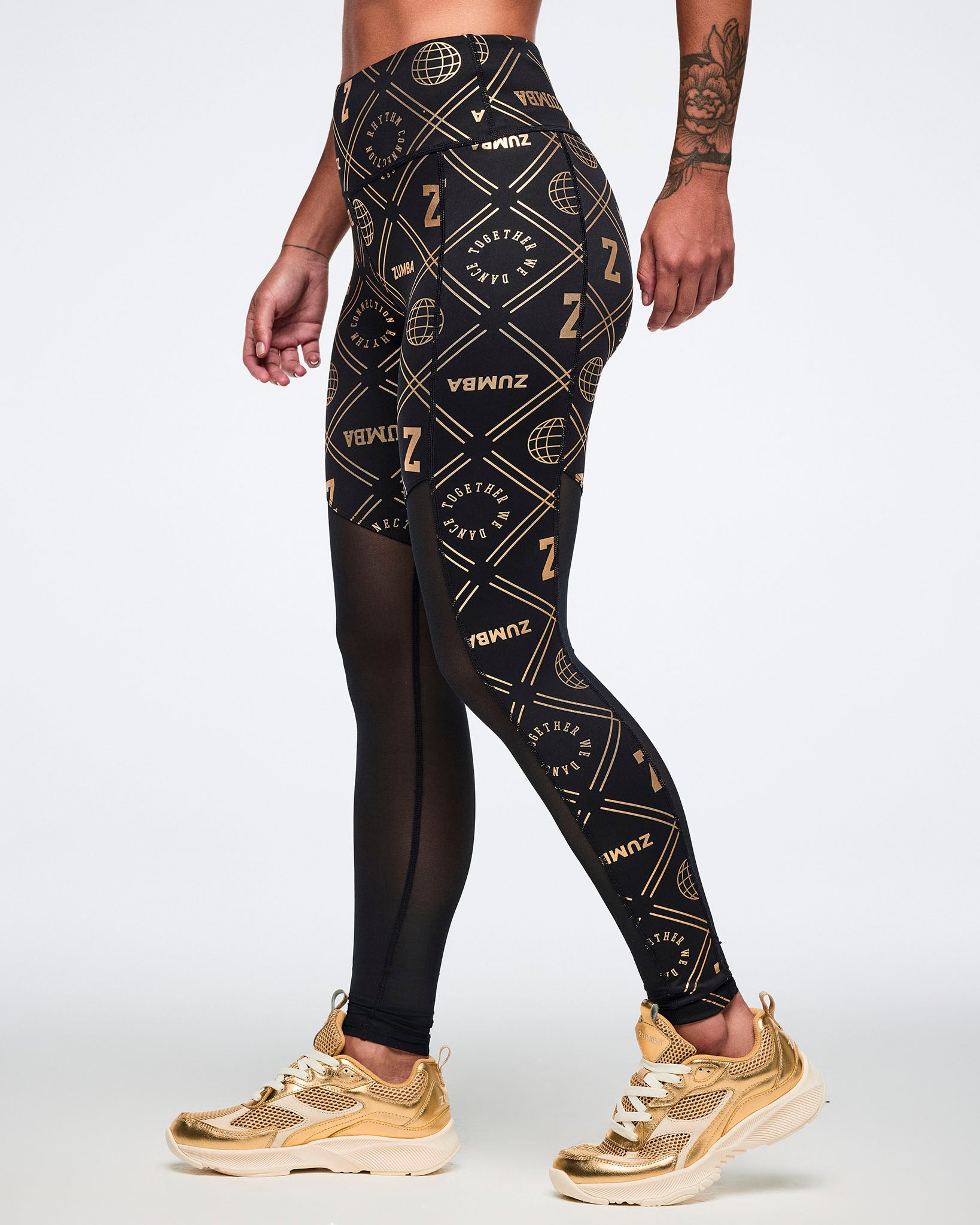 Female model wearing black leggings with gold geometric pattern paired with gold shoes.