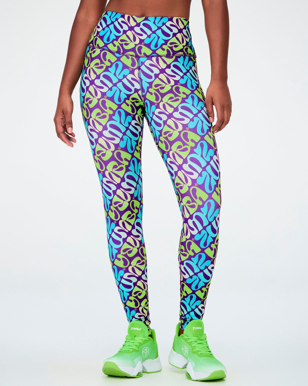 Female model in the purple, aqua, and neon green warped 'ZUMBA' print ankle leggings, showing the smooth high waistband and ankle-length hem.