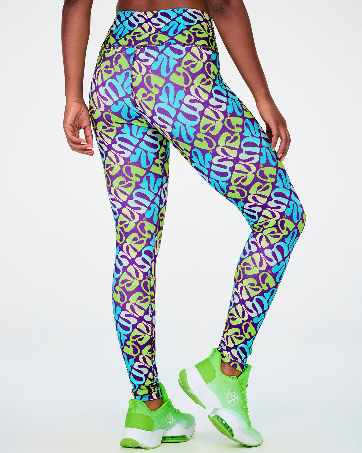 Shown from the back, the purple and aqua warped 'ZUMBA' print leggings, with the print wrapping around the high waistband and seat.