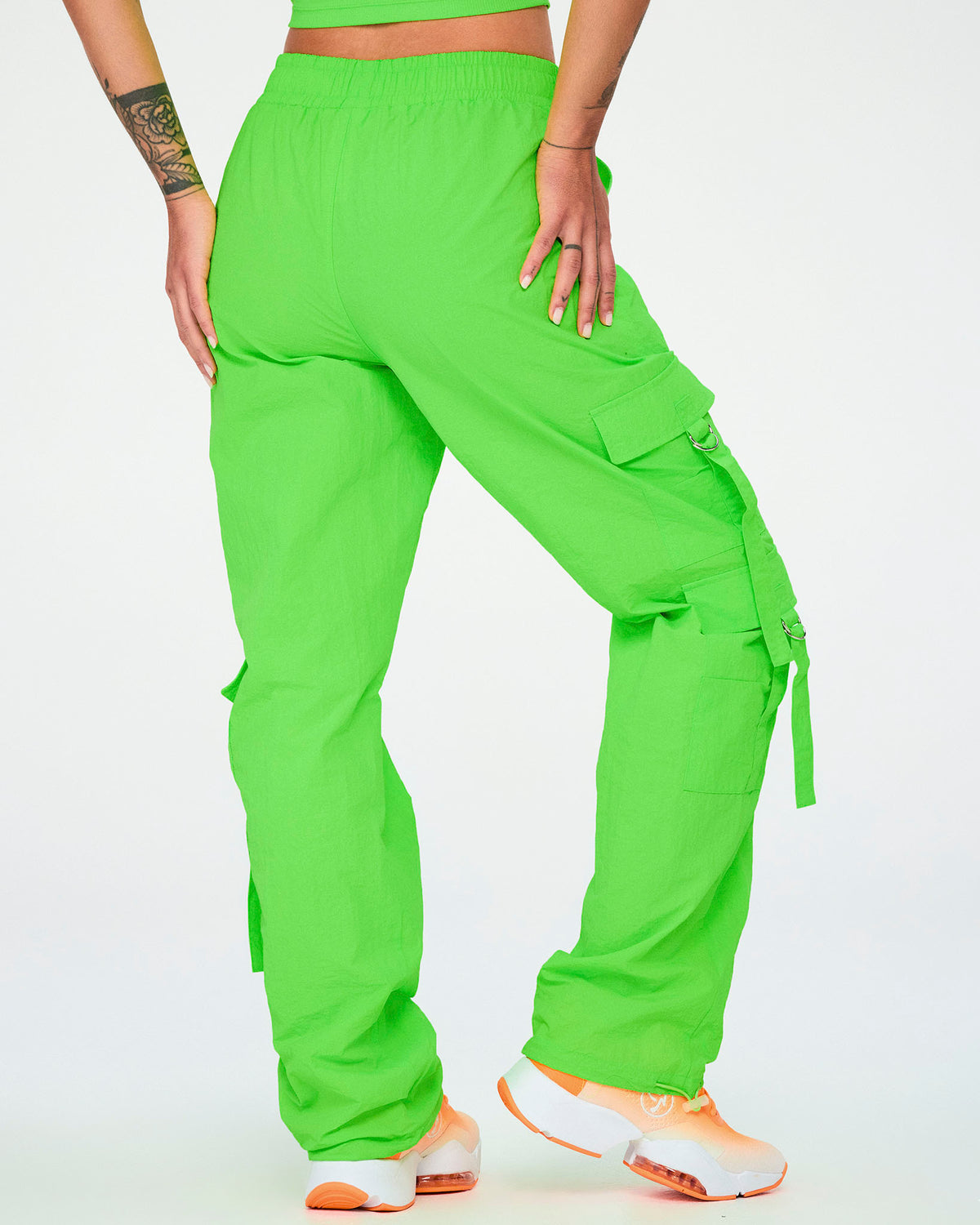 Back view of the neon green cargo pants with tassels, showing the side cargo pocket with a hanging tassel strap on the right leg.