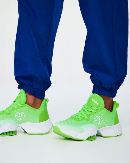 Close-up of the blue parachute cargo pants' elastic cuffs gathered at the ankles over neon green shoes.
