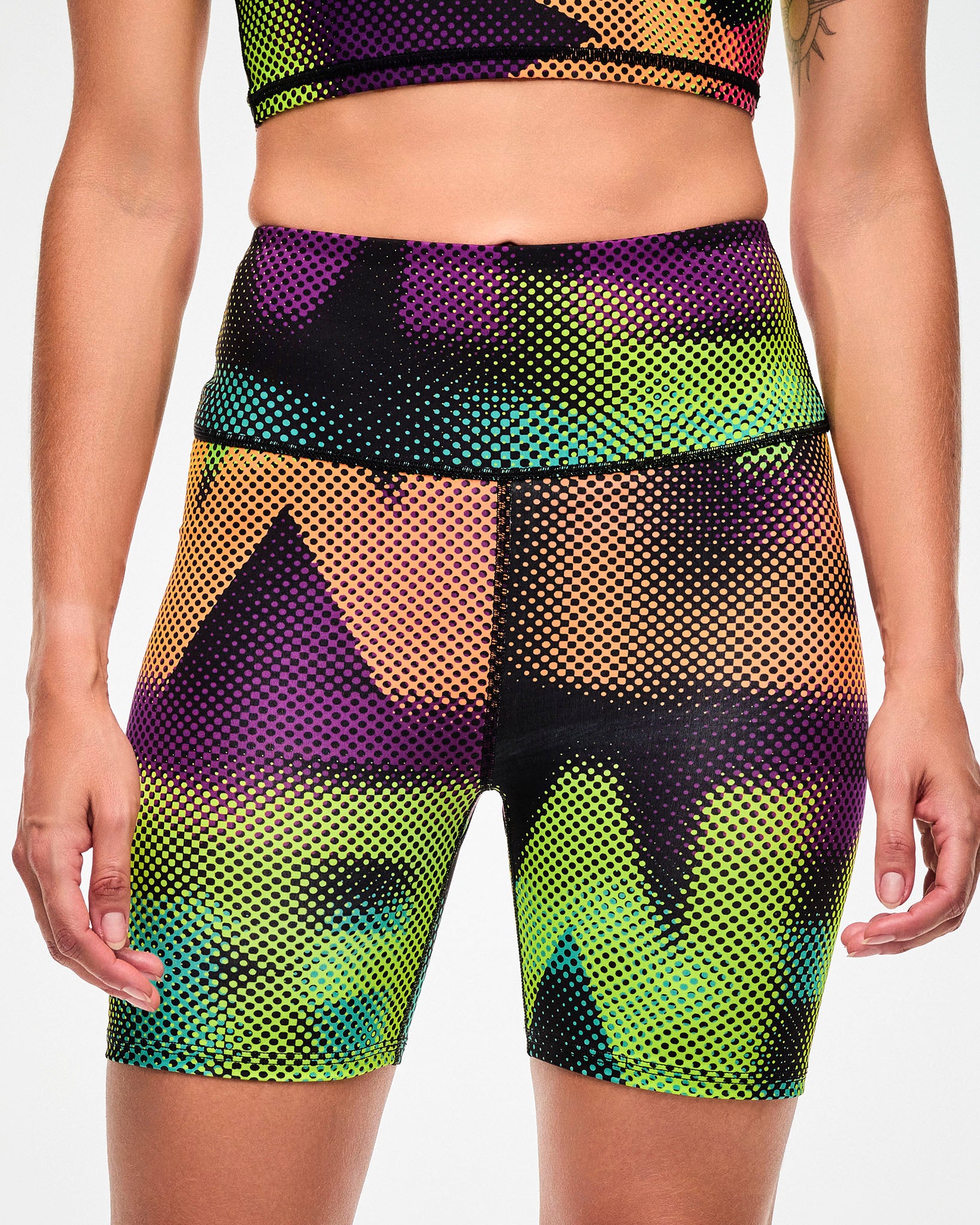 Close-up of pink, purple, orange, and aqua ombre biker shorts with a blurred, oversized "ZUMBA" wordmark print.