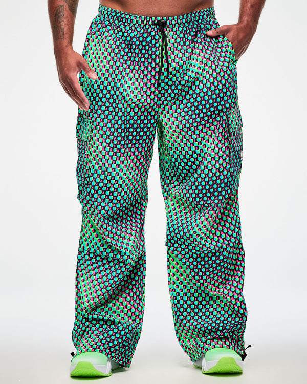 Close-up of a male model wearing green cargo pants with an aqua, black, and pink dot print, paired with green sneakers.