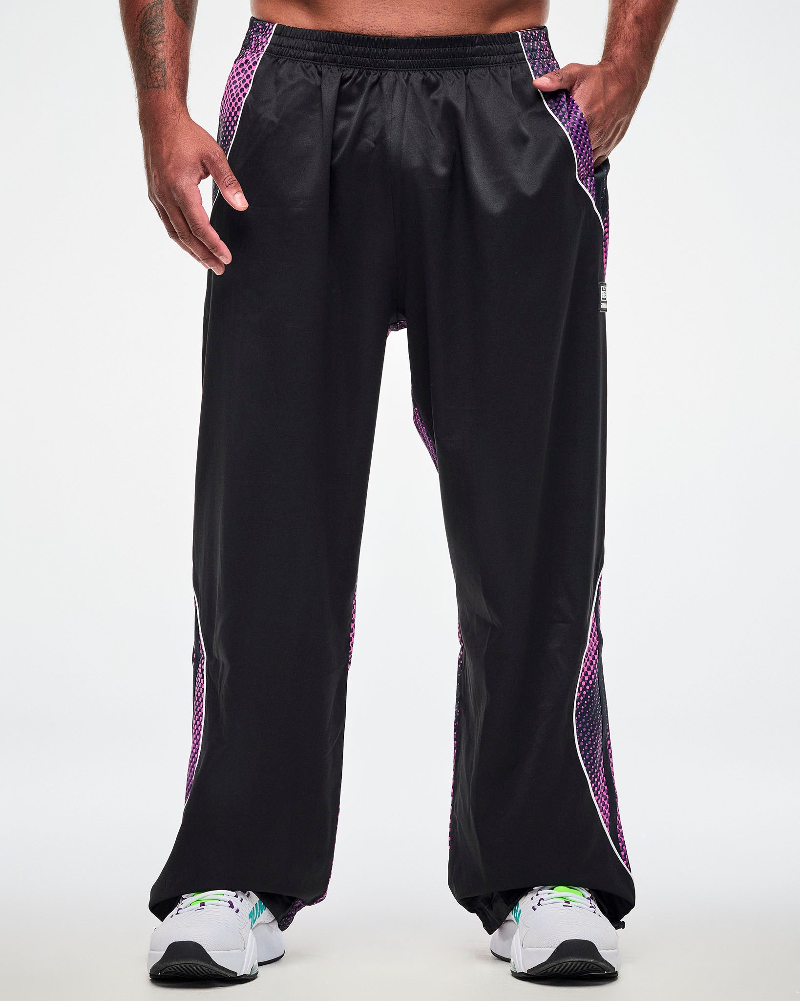Male model wearing black pants with a purple-to-pink dot gradient side and back panel and white sneakers.