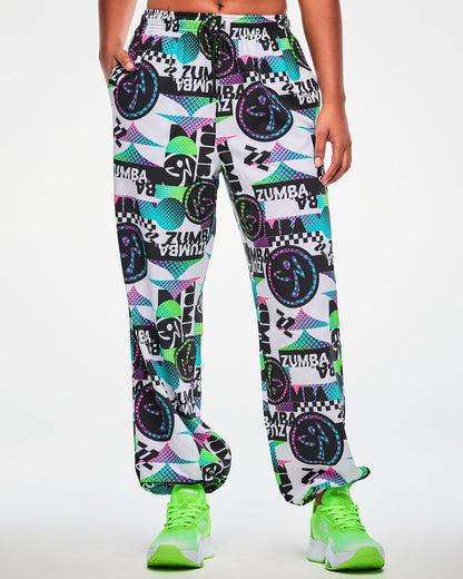 Female model wearing white track pants with an all-over abstract print, paired with green sneakers.