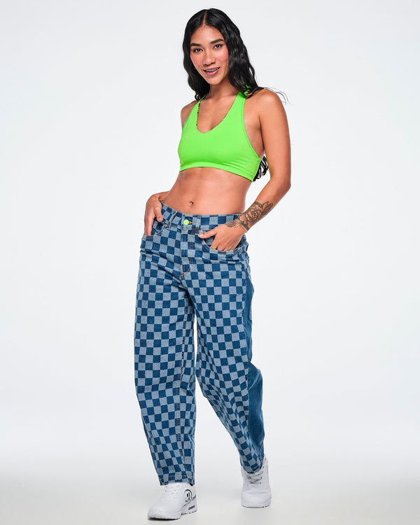 Full view of a female model in the checkerboard barrel ankle pants with a lime green halter bra and white shoes.