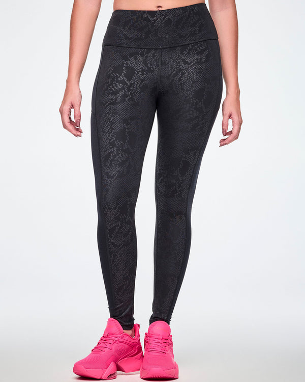 Front view of a female model wearing black high-waisted leggings with a subtle tonal snake-skin pattern and sheer mesh side panels, paired with pink shoes.