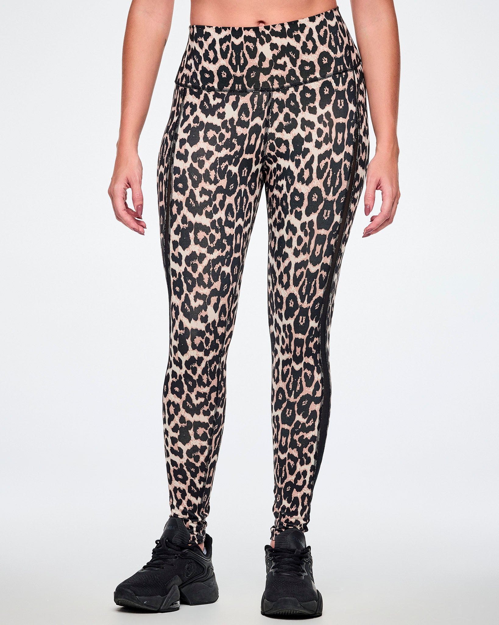 Front view of a female model wearing high-waisted leopard print leggings with sheer side panels, paired with black shoes.