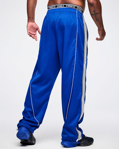 Back view of a male model wearing blue woven pants, paired with blue-and-black shoes.