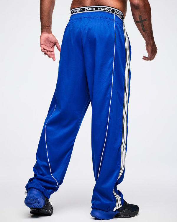 Back view of a male model wearing blue woven pants, paired with blue-and-black shoes.