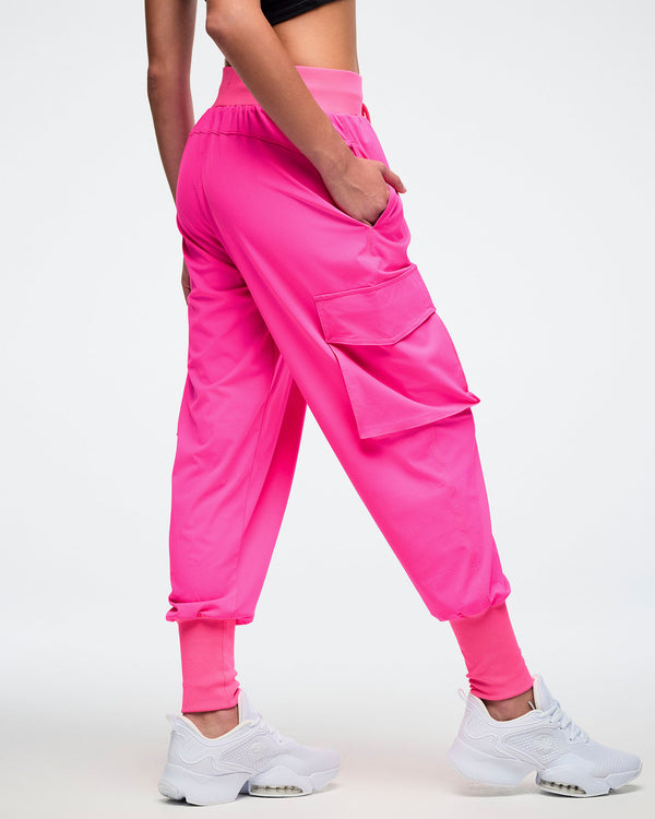 Back view of a female model wearing bright pink cargo pants showing off the plain pink cargo pocket.