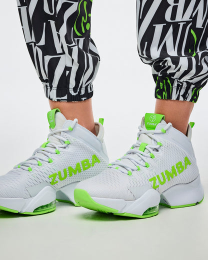 Close-up of the encased elastic cuffs on black-and-white patterned Zumba pants with green Zumbito accents, paired with green-and-white shoes.