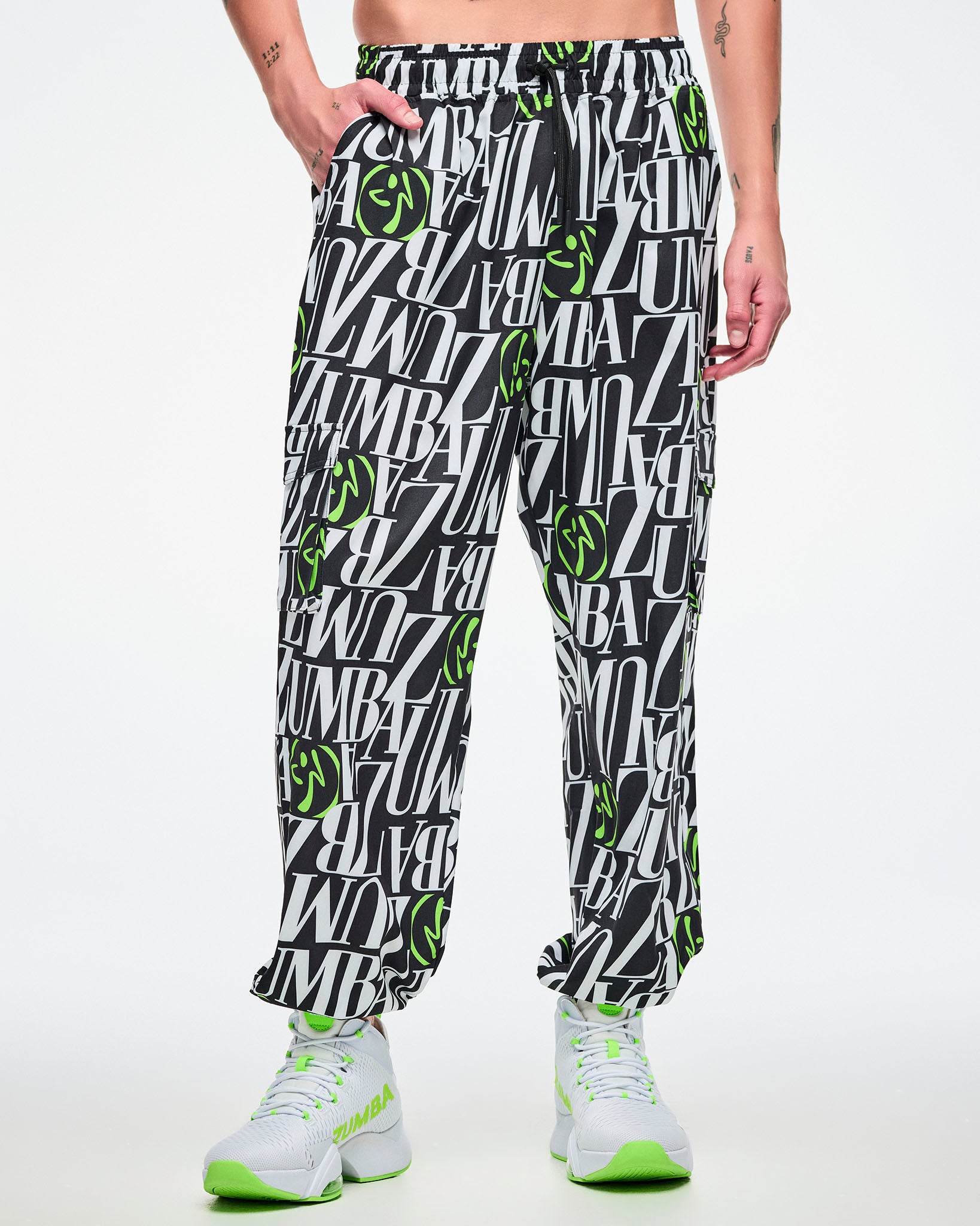 Male model with hand in his right pocket of the black and white patterned pants with green Zumbito accents on a white background.