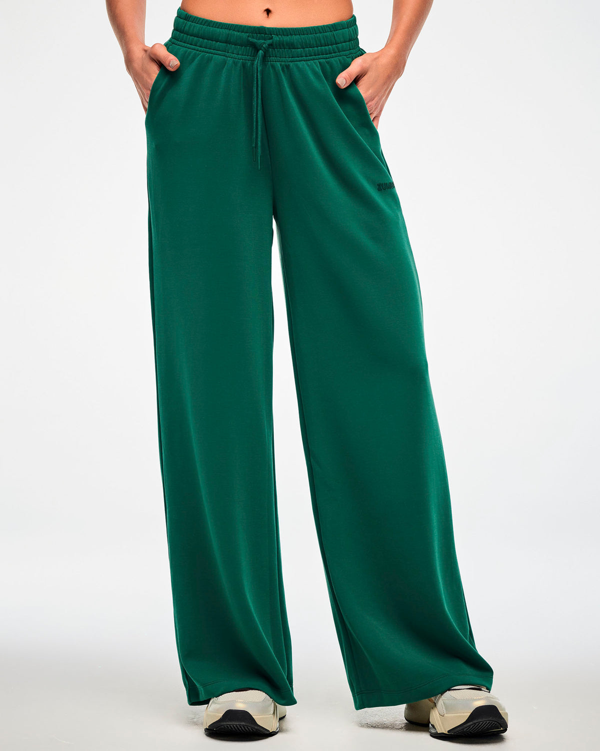 Female model in the teal green high-waisted pants, showing the relaxed fit from the drawcord waist down to the wide hems.