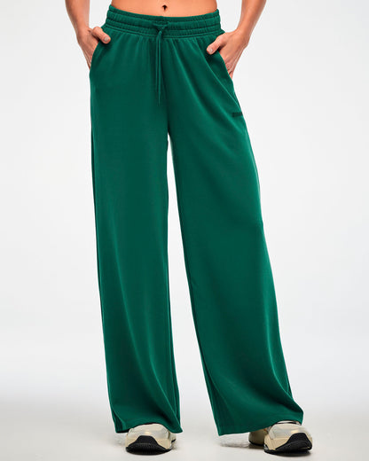 Female model in the teal green high-waisted pants, showing the relaxed fit from the drawcord waist down to the wide hems.