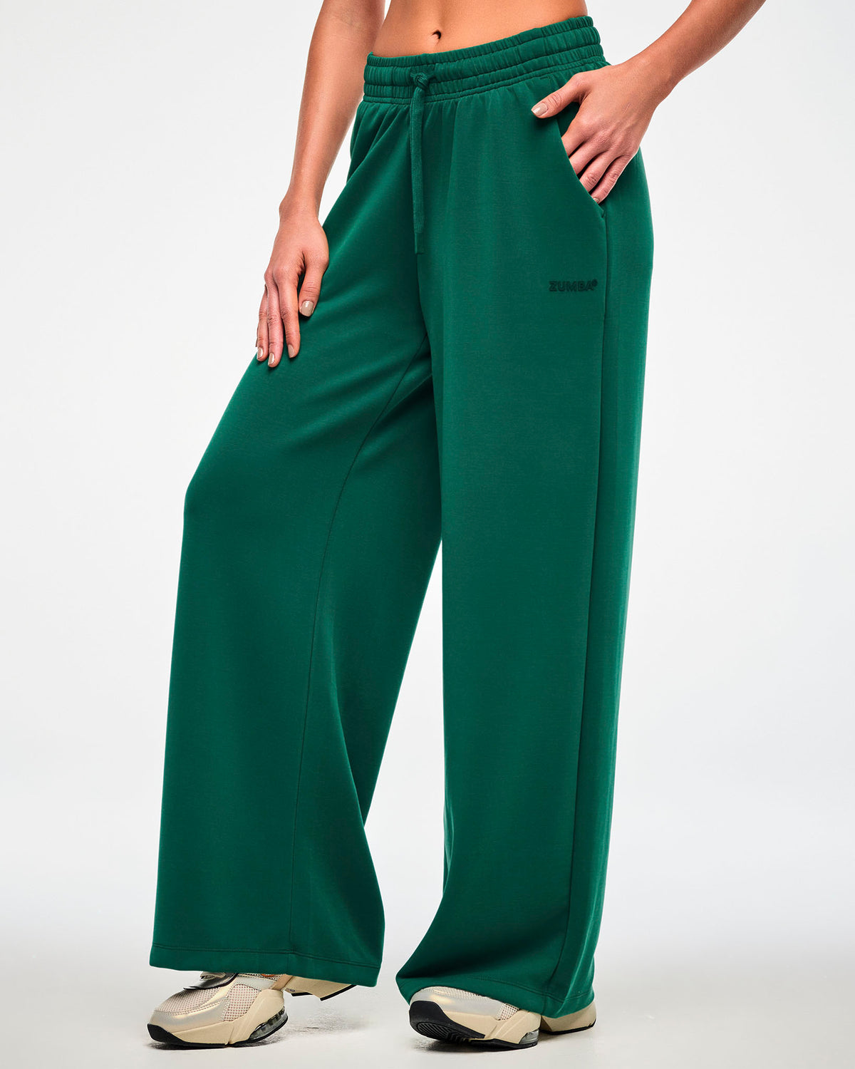 Female model in the teal green high-waisted pants, turned slightly to show the relaxed straight leg falling over beige shoes.
